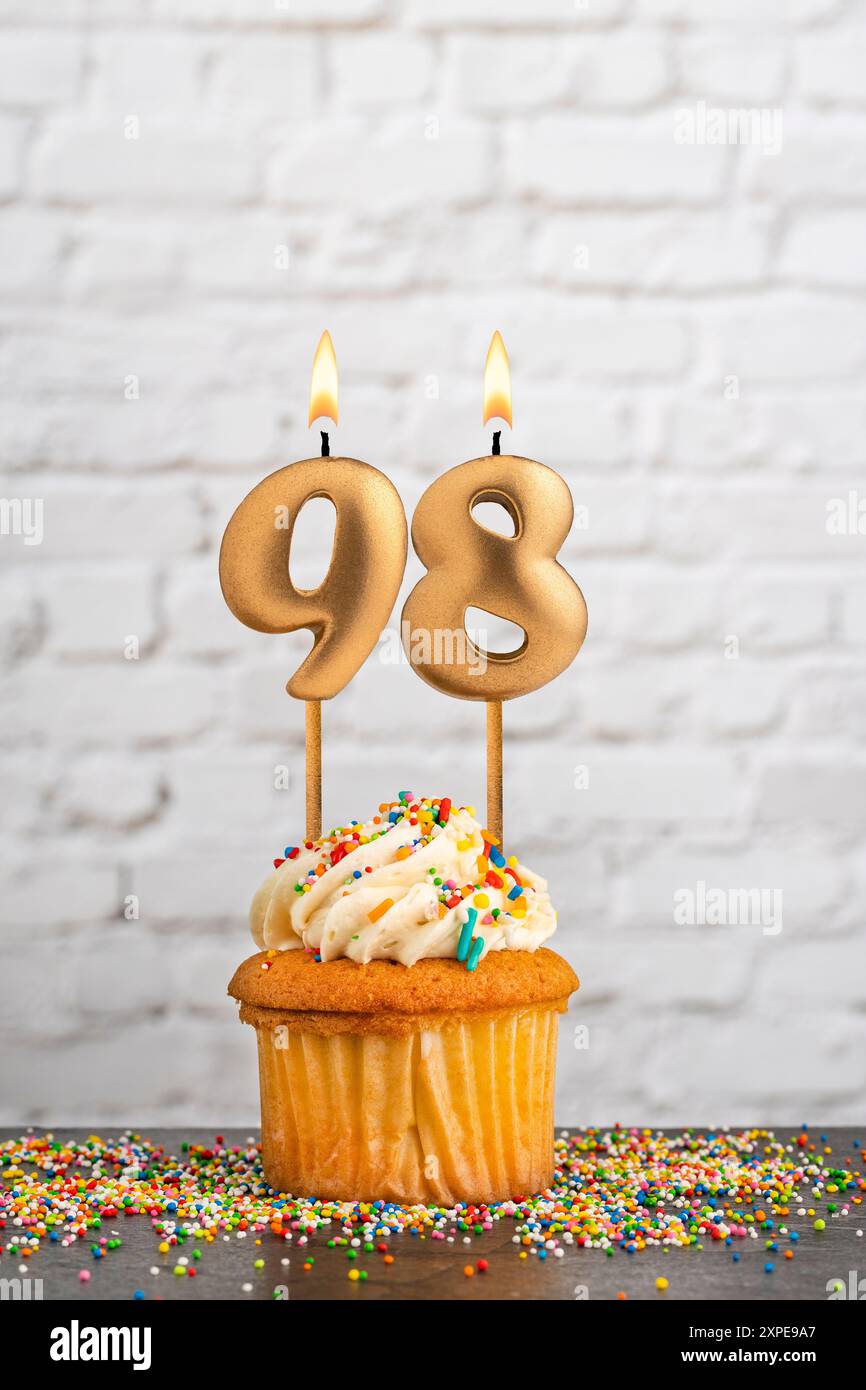 Cupcake avec numéro 98 bougie d'anniversaire - fond de mur de bloc blanc Banque D'Images