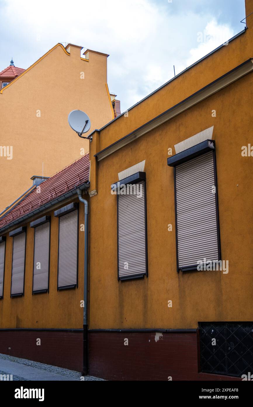Ruelle urbaine colorée avec fenêtres obturées et antenne parabolique par un jour ensoleillé Banque D'Images