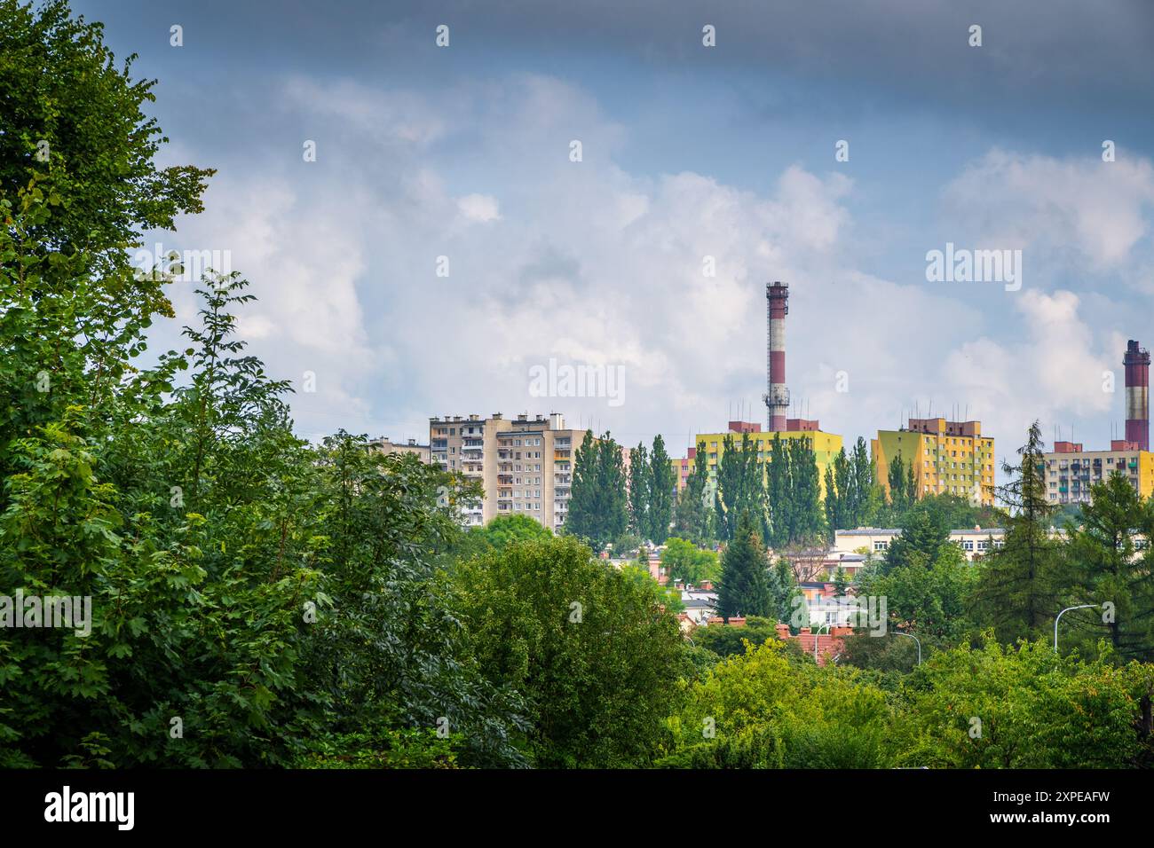 Horizon urbain avec cheminées industrielles entourées de verdure et de ciel nuageux Banque D'Images