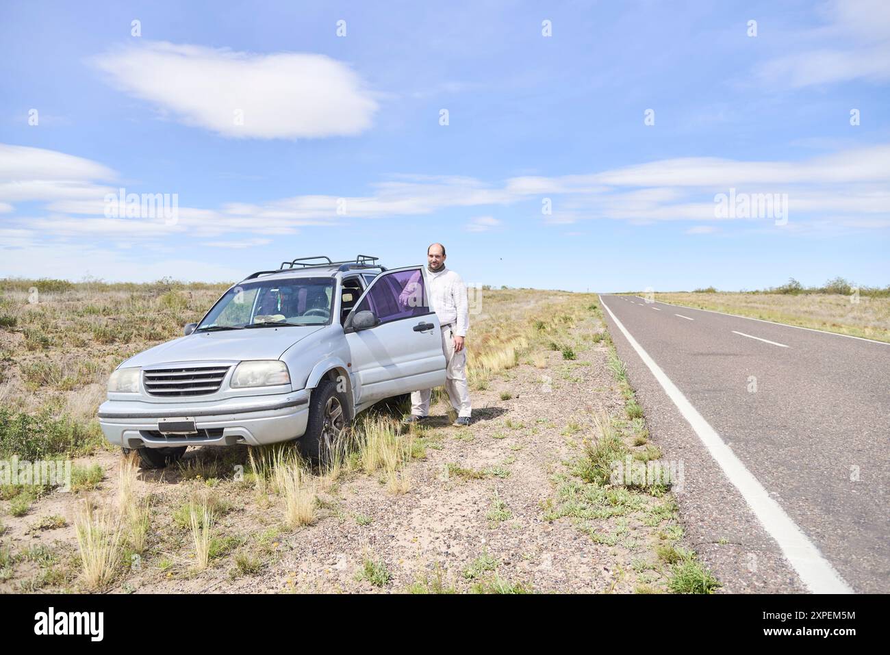 Scène de voyage, un arrêt sur la route : homme debout à côté de son véhicule, sur le point d'y entrer. Image qui transmet tranquillité et calme, composition avec flic Banque D'Images