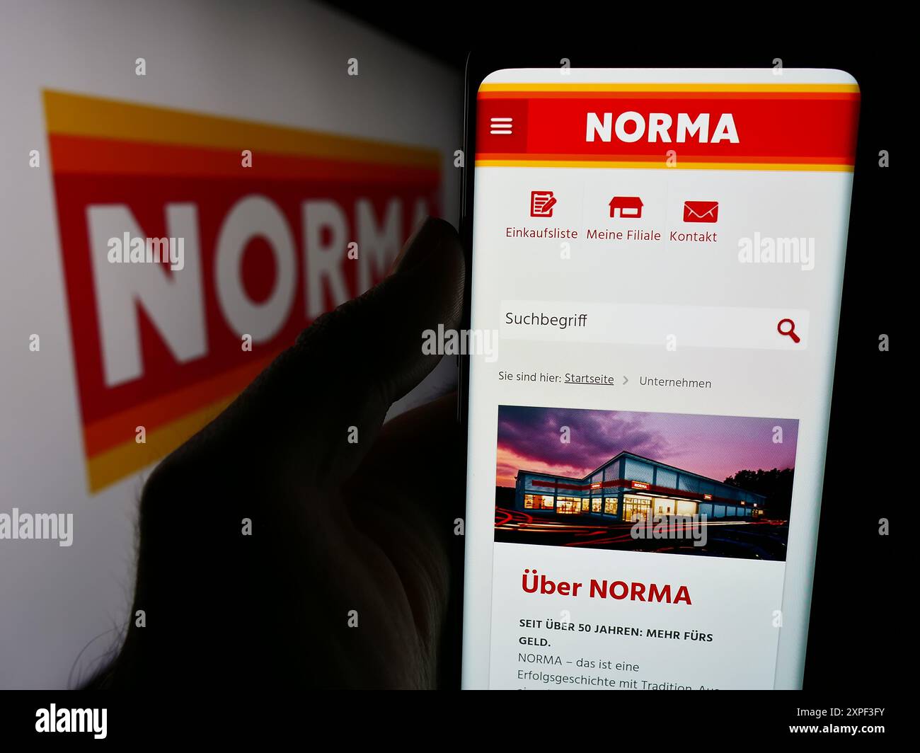 Personne tenant le téléphone portable avec le site de la société Norma Lebensmittelfilialbetrieb Stiftung Co. KG avec logo. Concentrez-vous sur le centre de l'écran du téléphone. Banque D'Images