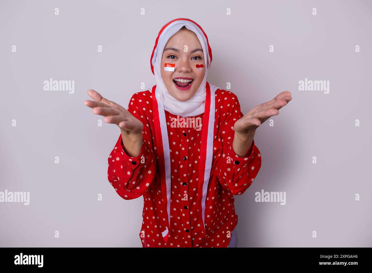 Une femme portant le hijab dans une tenue rouge polkadot et un bandeau de drapeau indonésien pose pour célébrer le jour de l'indépendance de l'Indonésie Banque D'Images