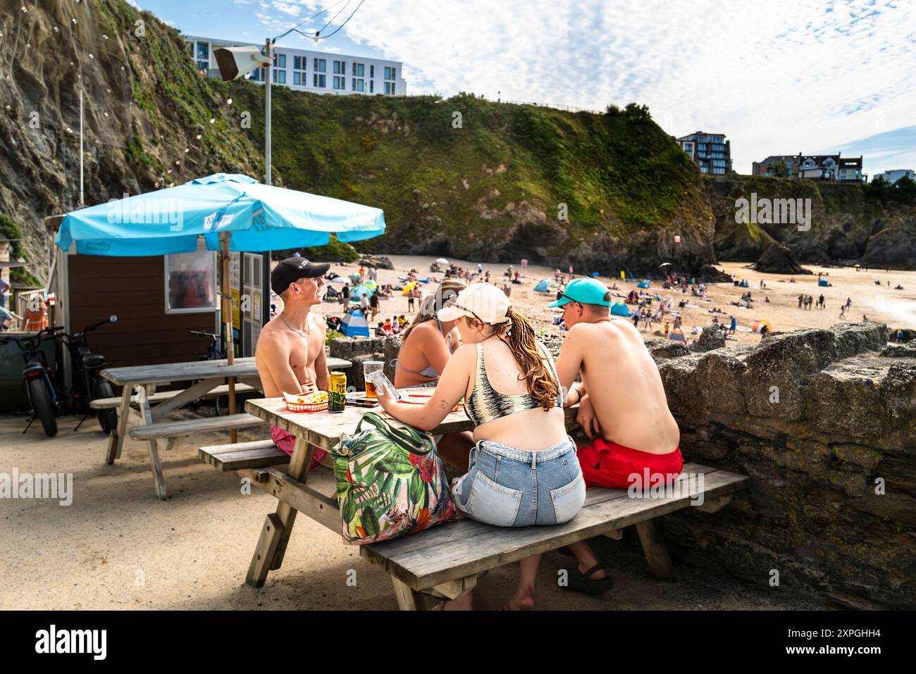 Vacanciers mangeant, buvant et se relaxant sur une table de pique-nique à GT Great Western Beach à Newquay en Cornouailles au Royaume-Uni. Banque D'Images Vacanciers mangeant, buvant et se relaxant sur une table de pique-nique à GT Great Western Beach à Newquay en Cornouailles au Royaume-Uni. Banque D'Images