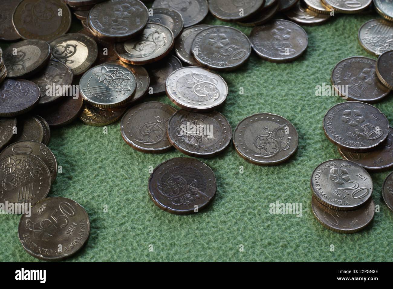 Terengganu, malaisie - 23 août 2024 : gros plan de pièces de monnaie malaisiennes dispersées sur fond vert Banque D'Images