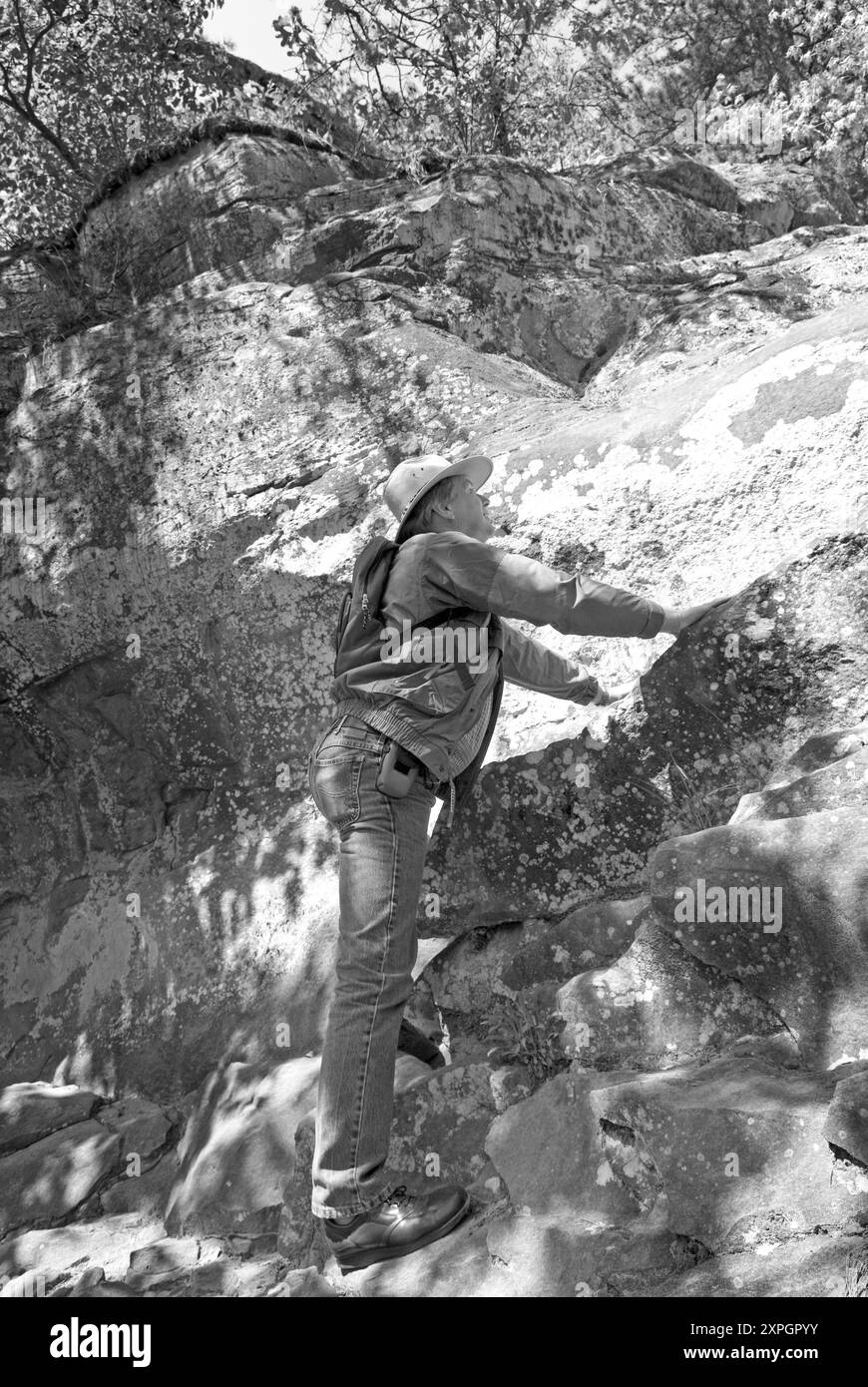 Un homme caucasien, âgé de 50 à 55 ans, grimpant un rocher sur l'un des nombreux sentiers de randonnée du parc d'État de petit Jean, près de Morrilton, Arkansas, États-Unis Banque D'Images
