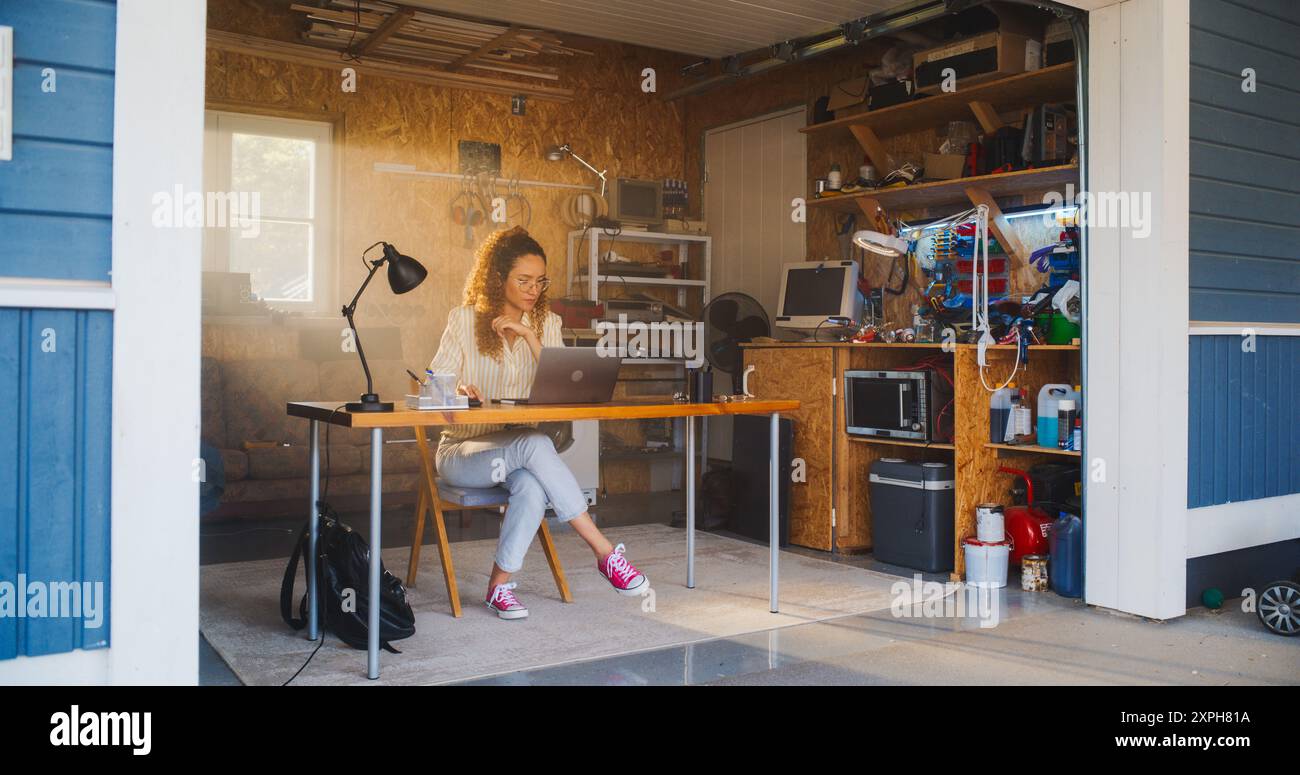 Programmation féminine hispanique sur ordinateur portable dans le garage à la maison. Jeune femme travaillant sur Innovative Software as A Service Startup for Business. Digital entrepreneur Starting Tech Company concept Banque D'Images