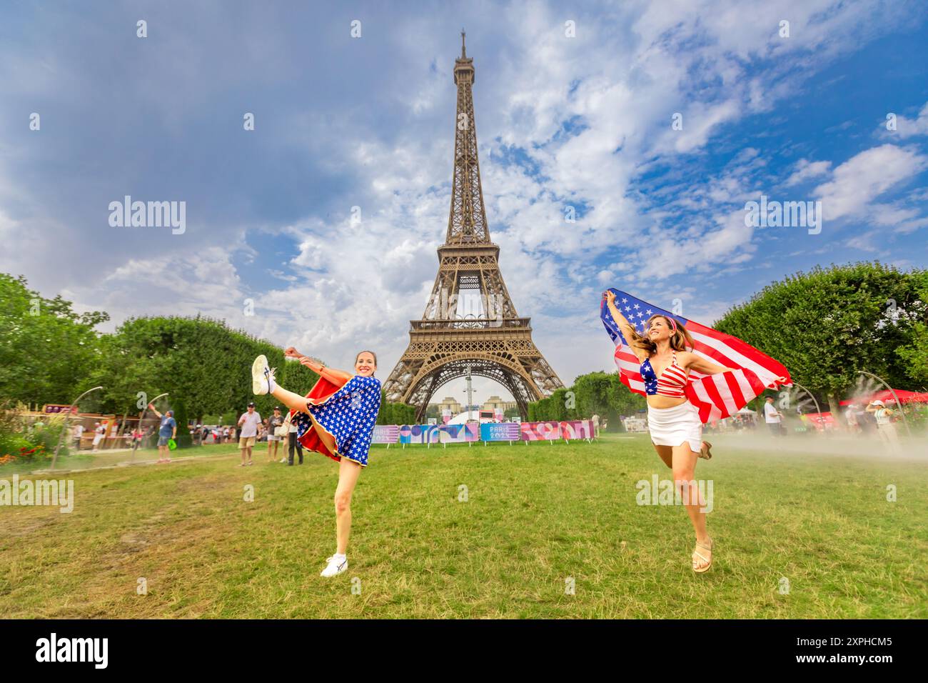 Femme américaine patriotique sautant et acclamant pour Team USA et les Jeux Olympiques de Paris 2024 devant la Tour Eiffel, Paris, France, Europe Banque D'Images
