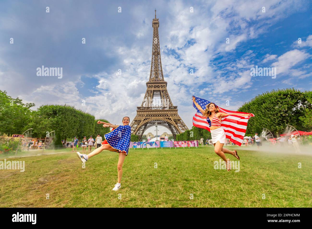 Femme américaine patriotique sautant et acclamant pour Team USA et les Jeux Olympiques de Paris 2024 devant la Tour Eiffel, Paris, France, Europe Banque D'Images