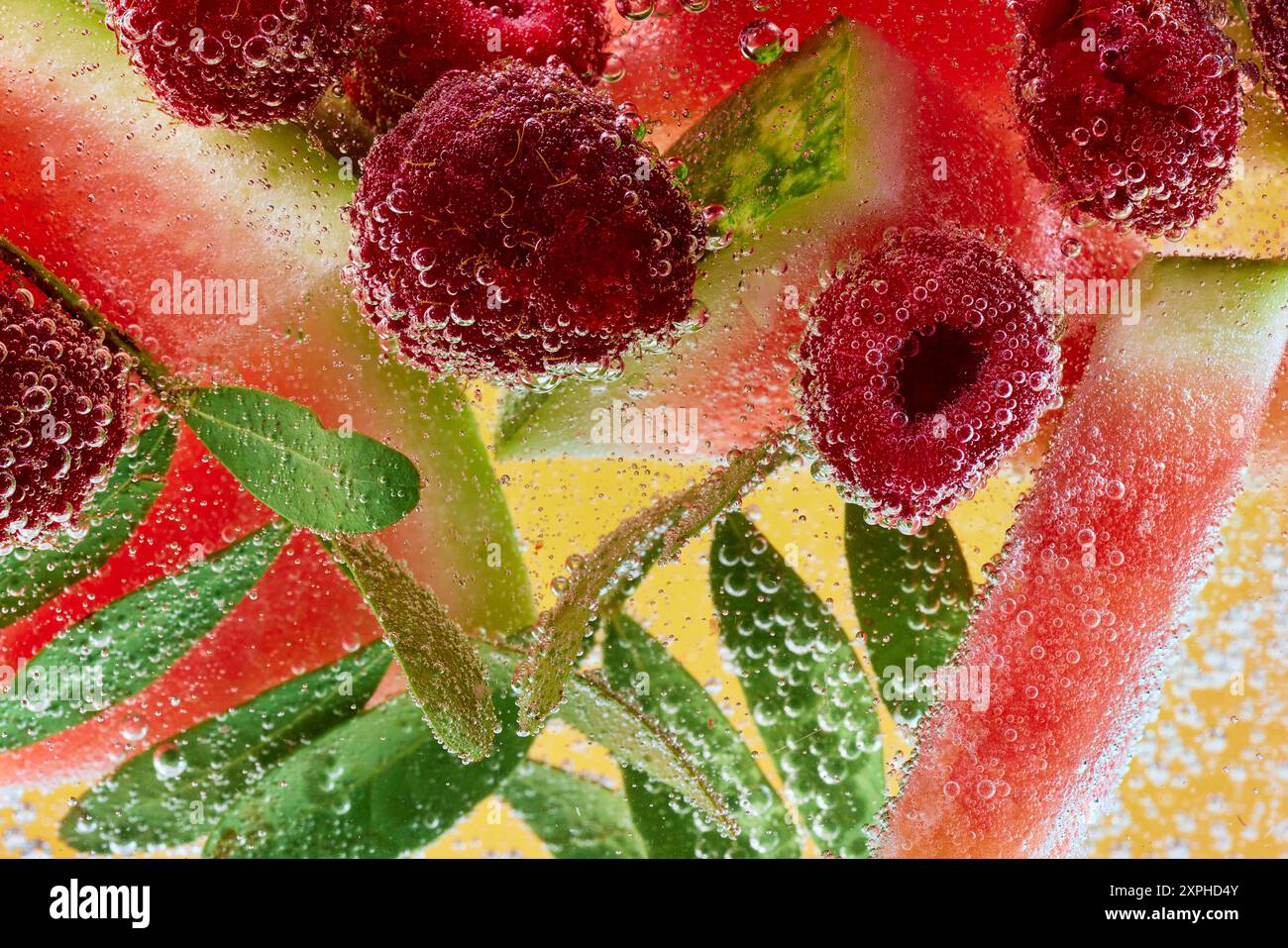 Pastèque fraîche et framboises avec des feuilles de menthe verte, immergées dans des bulles pétillantes. Gâterie estivale rafraîchissante. Banque D'Images