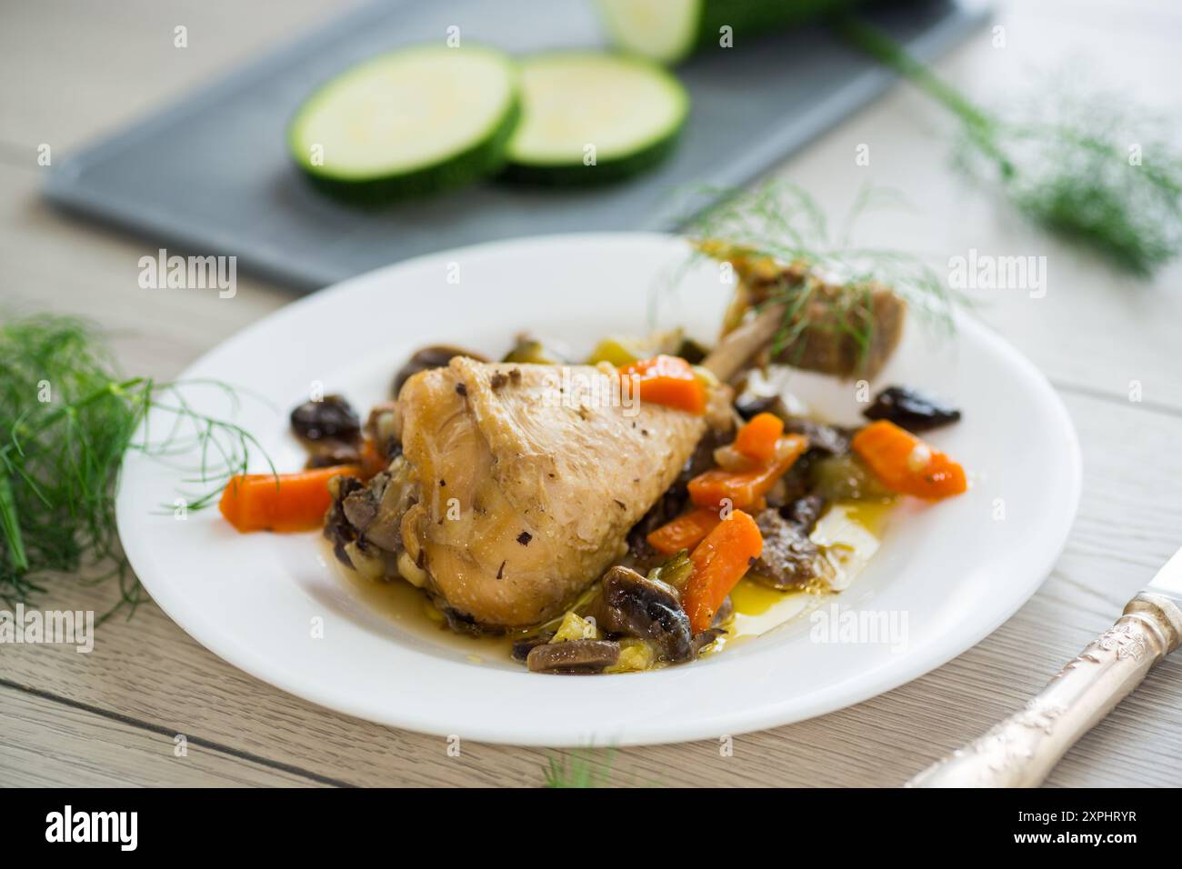 poulet rôti avec champignons et légumes dans une assiette sur une table en bois. Banque D'Images