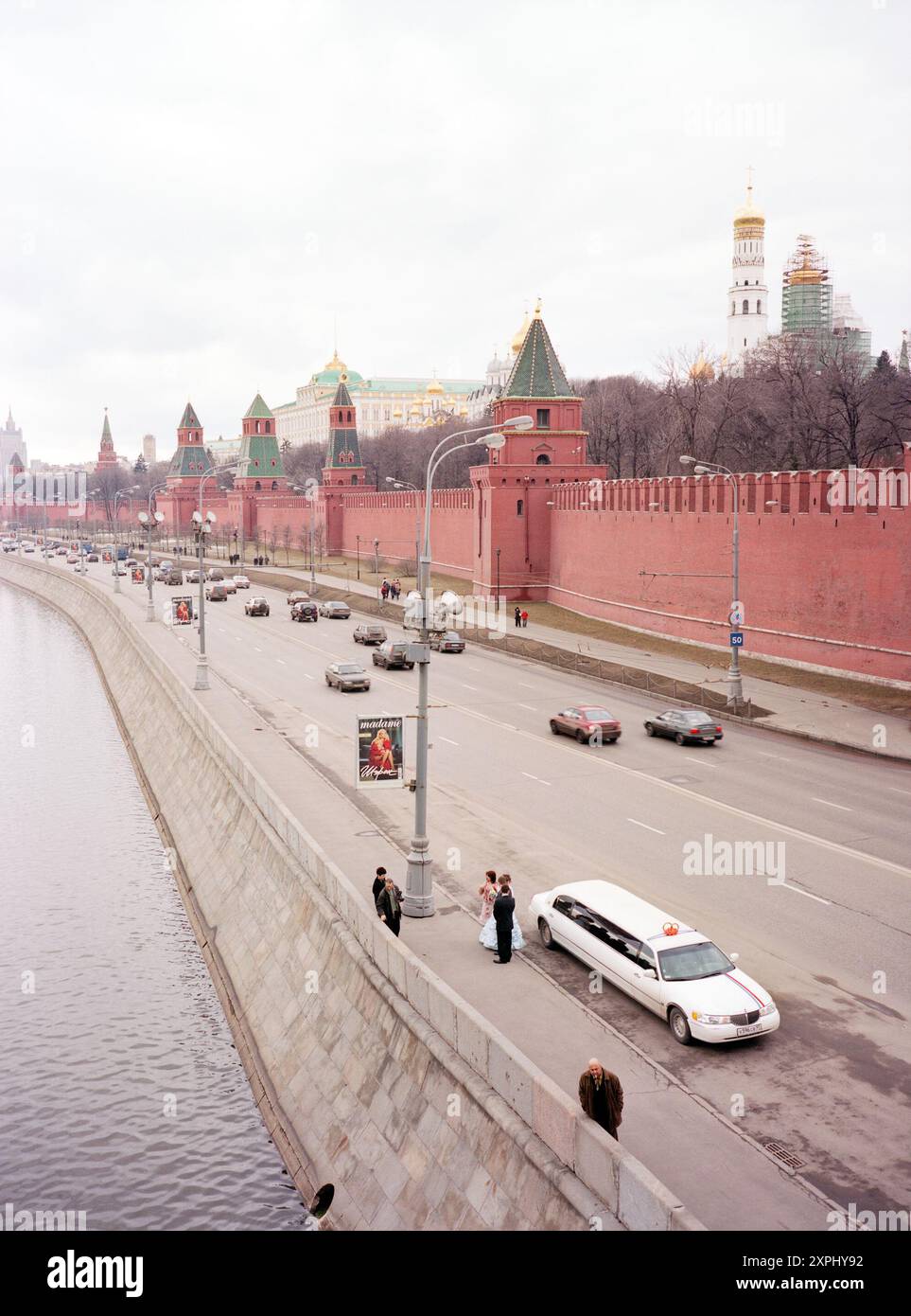 Un couple de mariage est photographié sur la rive de la rivière Moscou avec le Kremlin et une limousine en arrière-plan. Sur la droite, le Ivan le Grand clocher est visible. Moscou, avril 2006. Banque D'Images