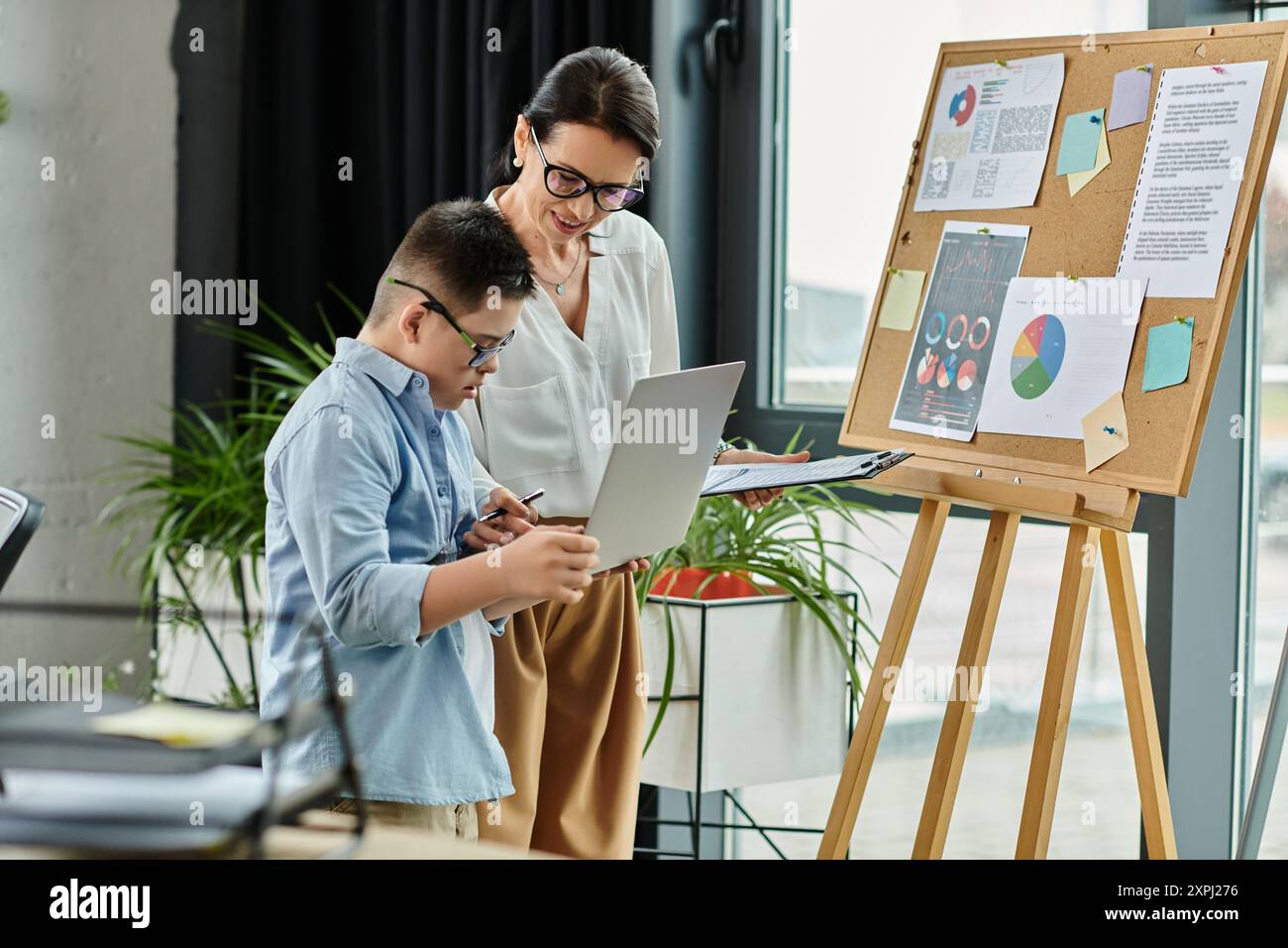 Une mère et son fils atteints du syndrome de Down travaillent ensemble sur un projet d'entreprise dans un cadre de bureau. Banque D'Images