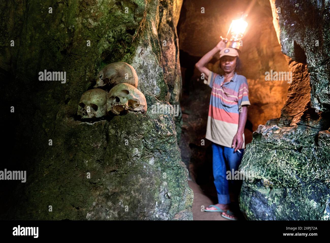 Un guide tenant une lanterne illumine un crâne humain dans une grotte du cimetière antique de Londa, cimetière de la grotte de Toraja, Tana Toraja, Sulawesi, Indonésie Banque D'Images