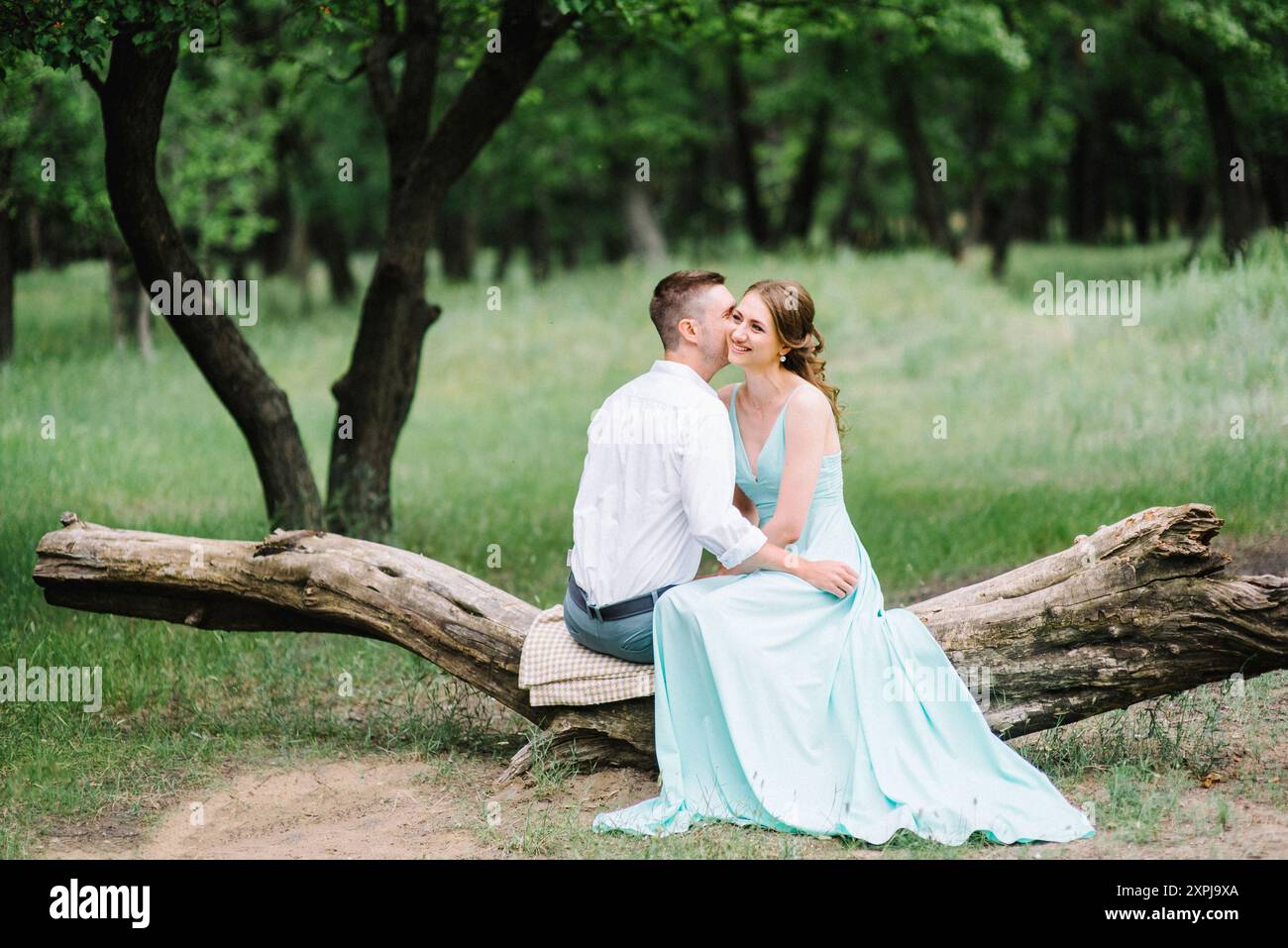 un homme heureux dans une chemise blanche et une fille dans une robe turquoise, la mariée et le marié marchent dans le parc forestier Banque D'Images