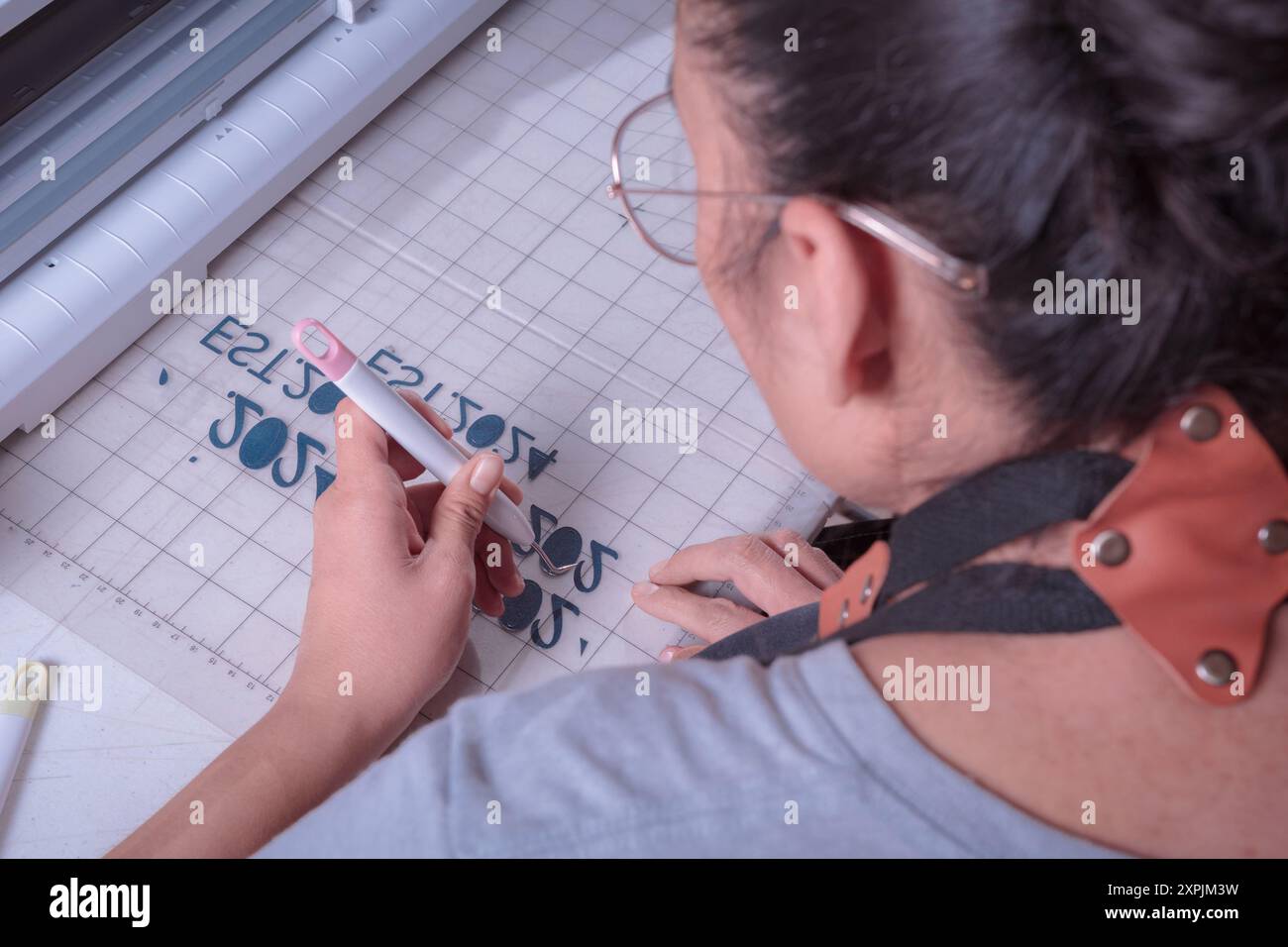 Jeune femme enlève l'excès de matériau avec l'outil de désherbage, lieu de travail avec traceur de coupe, outils, mise au point sélective. Banque D'Images