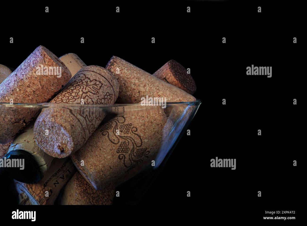 Macro photo de bouchons de bouteille de vin aléatoires dans un verre à martini. Fond noir avec espace pour la copie. Banque D'Images