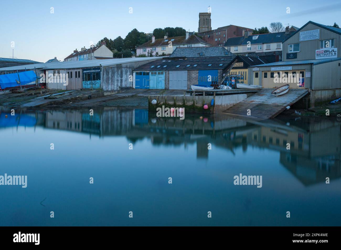 Plan de longue exposition de Batson Creek créant une eau miroir avec un reflet de l'arrière des chantiers navals de Island Street avec l'église à l'arrière Banque D'Images