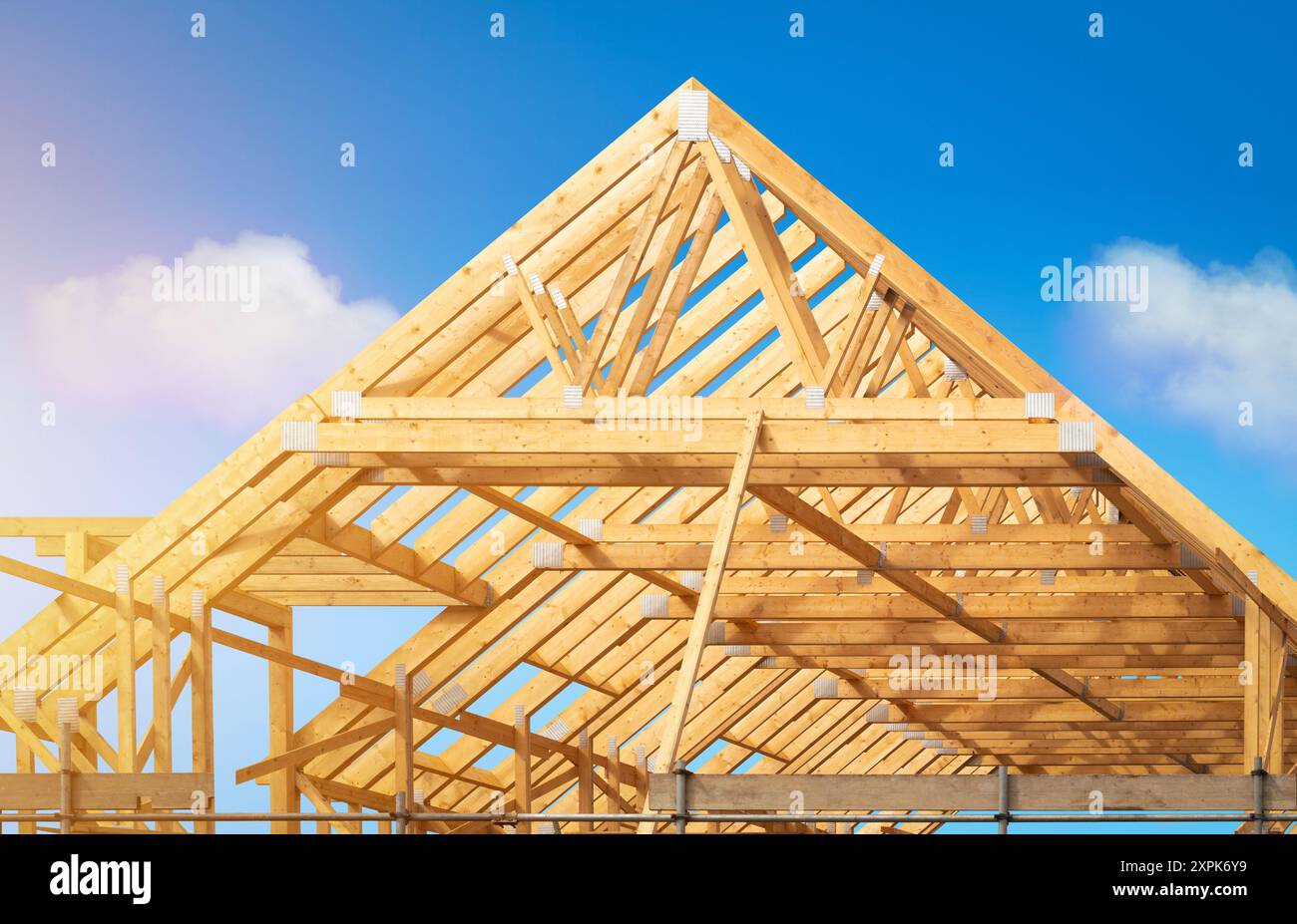 Construction - étape de charpente en bois d'un nouveau grenier de maison résidentielle utilisant des fermes pour la structure de toit. Un chantier de construction posé contre un ciel bleu clair. Banque D'Images