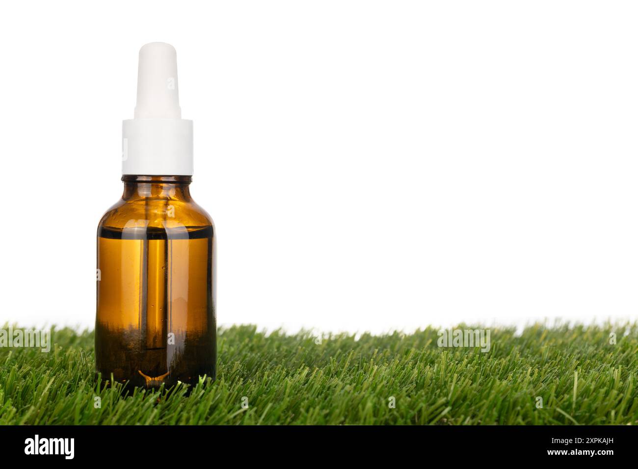 Bouteille compte-gouttes en verre ambré sur herbe Banque D'Images