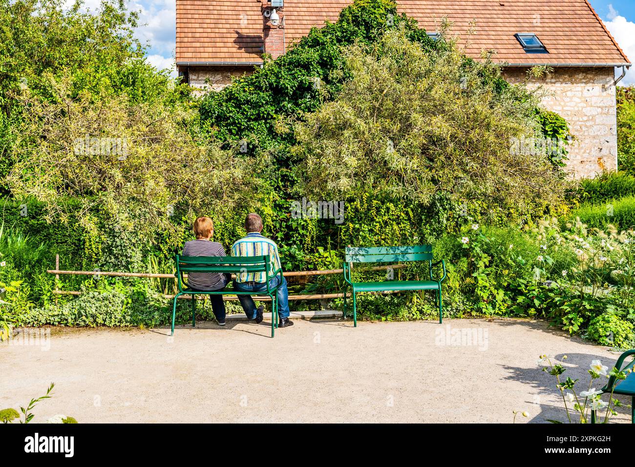 Un couple assis sur un banc dans le jardin coloré du Musée des impressionnismes de Giverny, où vécut le peintre français Claude Monet, en Normandie Banque D'Images