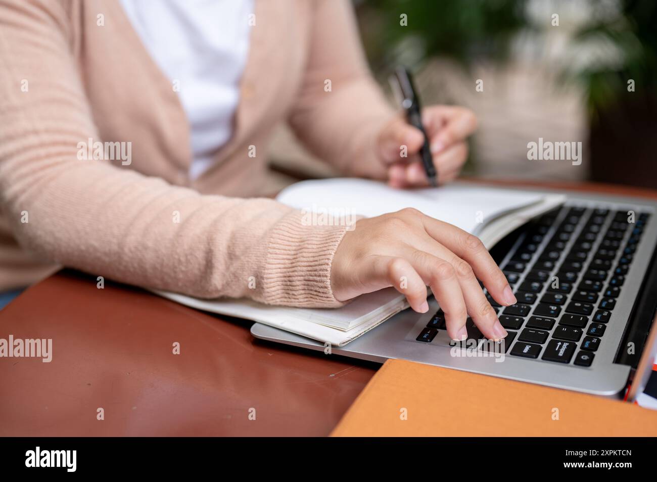 Une image recadrée d'une femme dans un cardigan tapant sur un clavier d'ordinateur portable ou en appuyant sur le bouton entrée pour mettre en pause une vidéo tout en étudiant un cours en ligne sur h. Banque D'Images