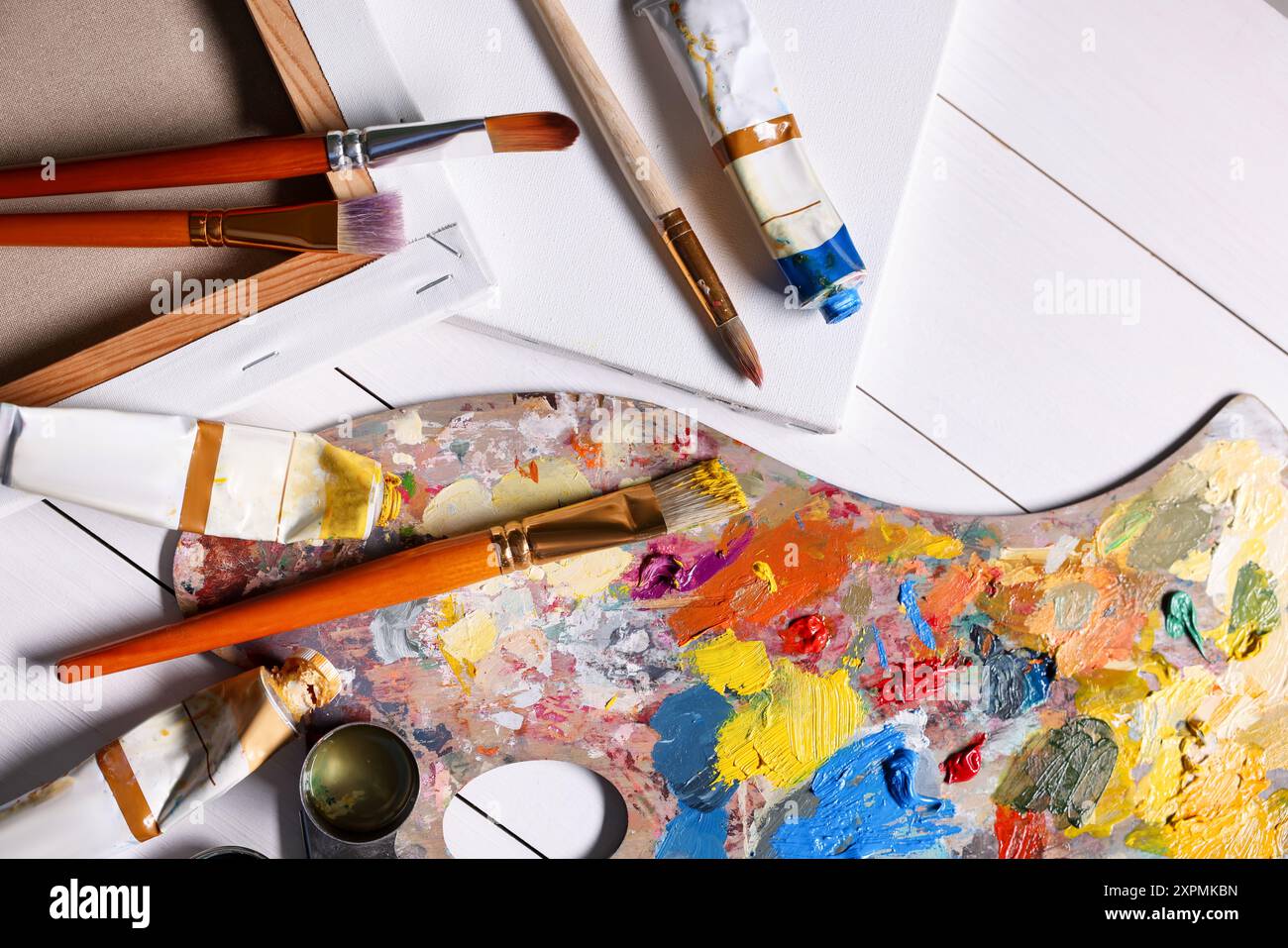 Palette d'artiste, pinceaux, peintures et toiles vierges sur table en bois blanc, pose à plat Banque D'Images