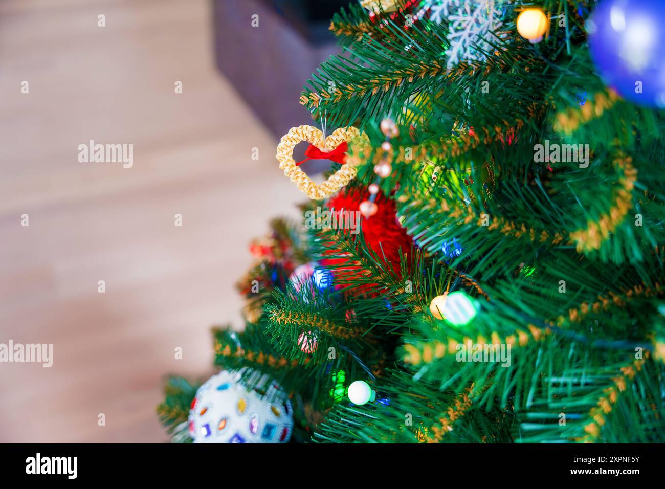 Ornement coeur de paille sur un arbre de Noël coloré Banque D'Images