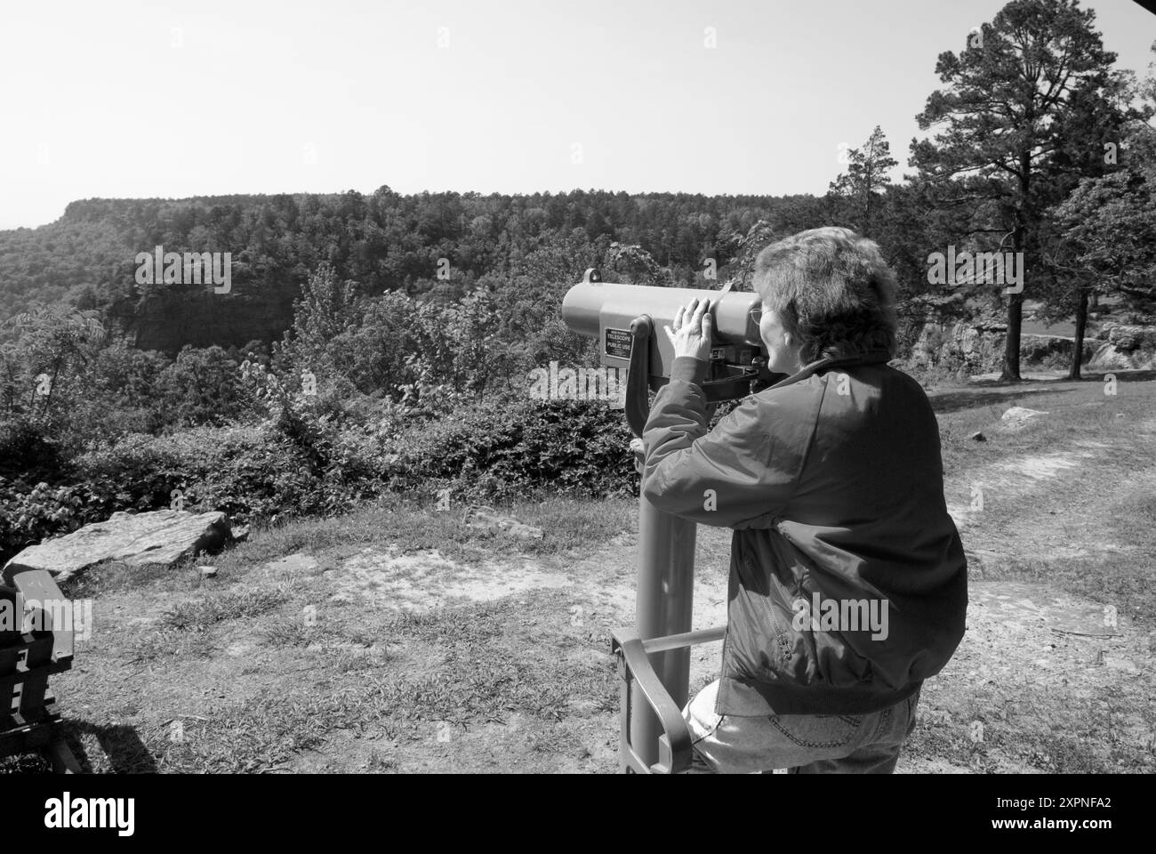 Femme caucasienne, âgée de 50 à 55 ans, observant les chutes de Cedar Creek à travers un télescope au petit Jean State Park, Arkansas.USA. Banque D'Images