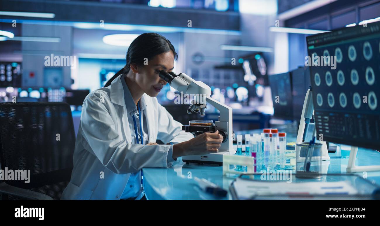 Laboratoire de développement de la médecine : scientifique féminin asiatique utilisant le microscope, analyse l'échantillon de boîte de Petri. Grand laboratoire pharmaceutique avec des spécialistes menant des recherches en biotechnologie, développant de nouveaux médicaments. Banque D'Images