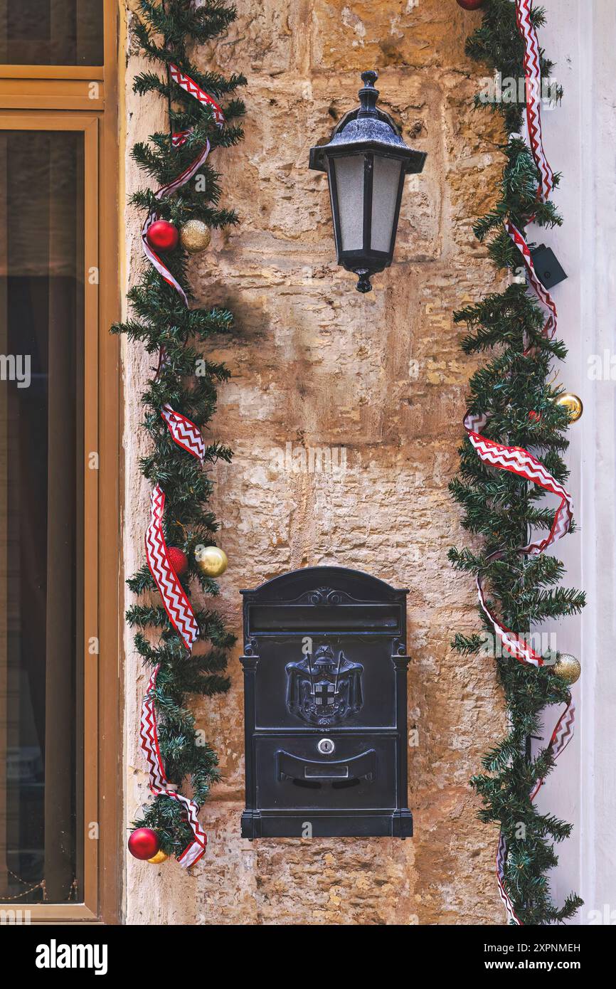 Fenêtre et mur avant en briques de l'ancienne maison résidentielle décorée pour les vacances de Noël avec des arbres à couronne et guirlande. Banque D'Images