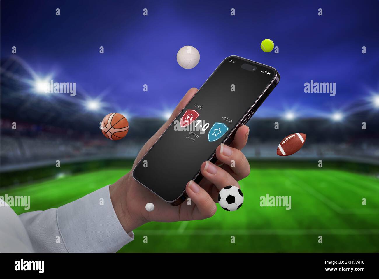 Téléphone en main avec une application de score en direct affichée à l'écran, sur fond de stade de football. Les ballons de sport volent autour du téléphone, emphas Banque D'Images