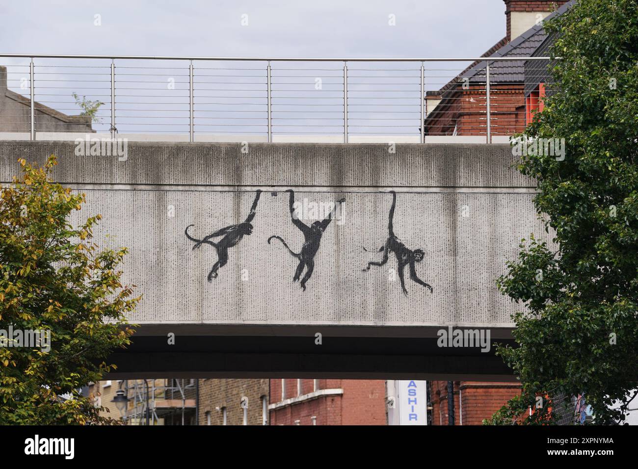 Une nouvelle œuvre représentant trois singes dévoilée par Banksy, peinte sur un pont à Brick Lane, à l'est de Londres. La dernière œuvre de l'artiste intervient un jour après qu'il a dévoilé deux éléphants qui sortent la tête de fenêtres bloquées peintes sur le flanc d'un bâtiment à Chelsea, au sud-ouest de Londres. Date de la photo : mercredi 7 août 2024. Banque D'Images