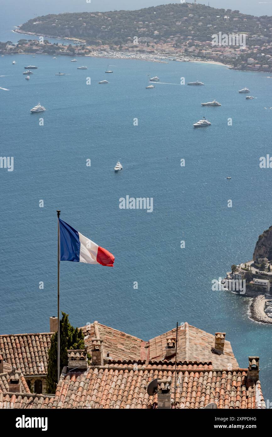 Drapeau français agitant au vent avec la mer bleue et des yachts en arrière-plan à Nice, France Banque D'Images