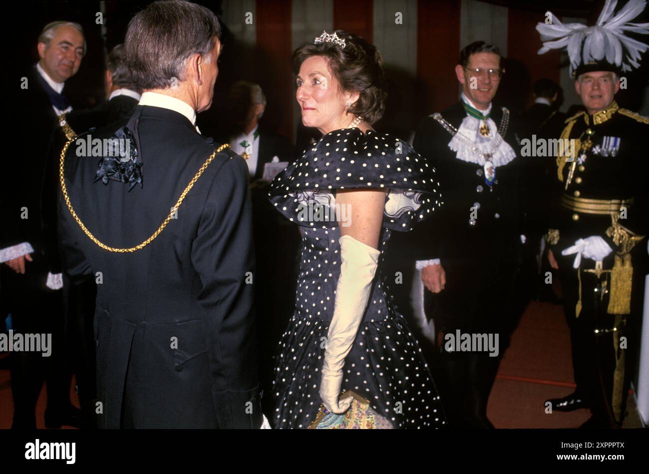 City of London années 1990 dans une robe à pois noirs avec des manches courtes bouffantes et de longs gants blancs pour enfants ; couronnée d'une diadème en diamant Mme Carolyn Graham, la Lady Mayoress fait de petites conversations avec des hommes d'affaires de la ville à paon plumé et enchaînés d'or après un banquet au Guildhall. 1990 ROYAUME-UNI HOMER SYKES Banque D'Images