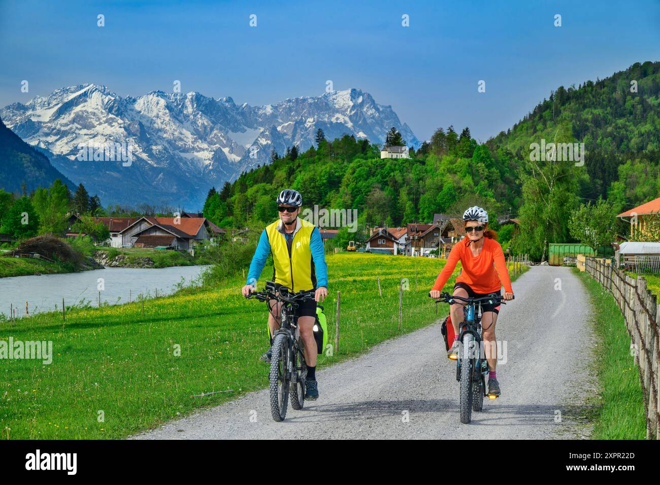 Homme et femme à vélo sur la piste cyclable du lac Constance-Königssee le long de la rivière Loisach, Zugspitze en arrière-plan, Eschenlohe, haute-Bavière, Bava Banque D'Images