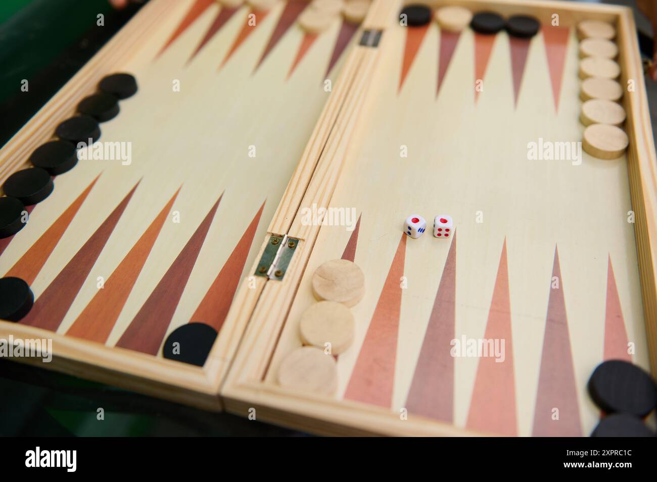 Gros plan d'une planche de backgammon traditionnelle en bois, avec des pièces noires et blanches et deux dés, prêt pour un match. Banque D'Images