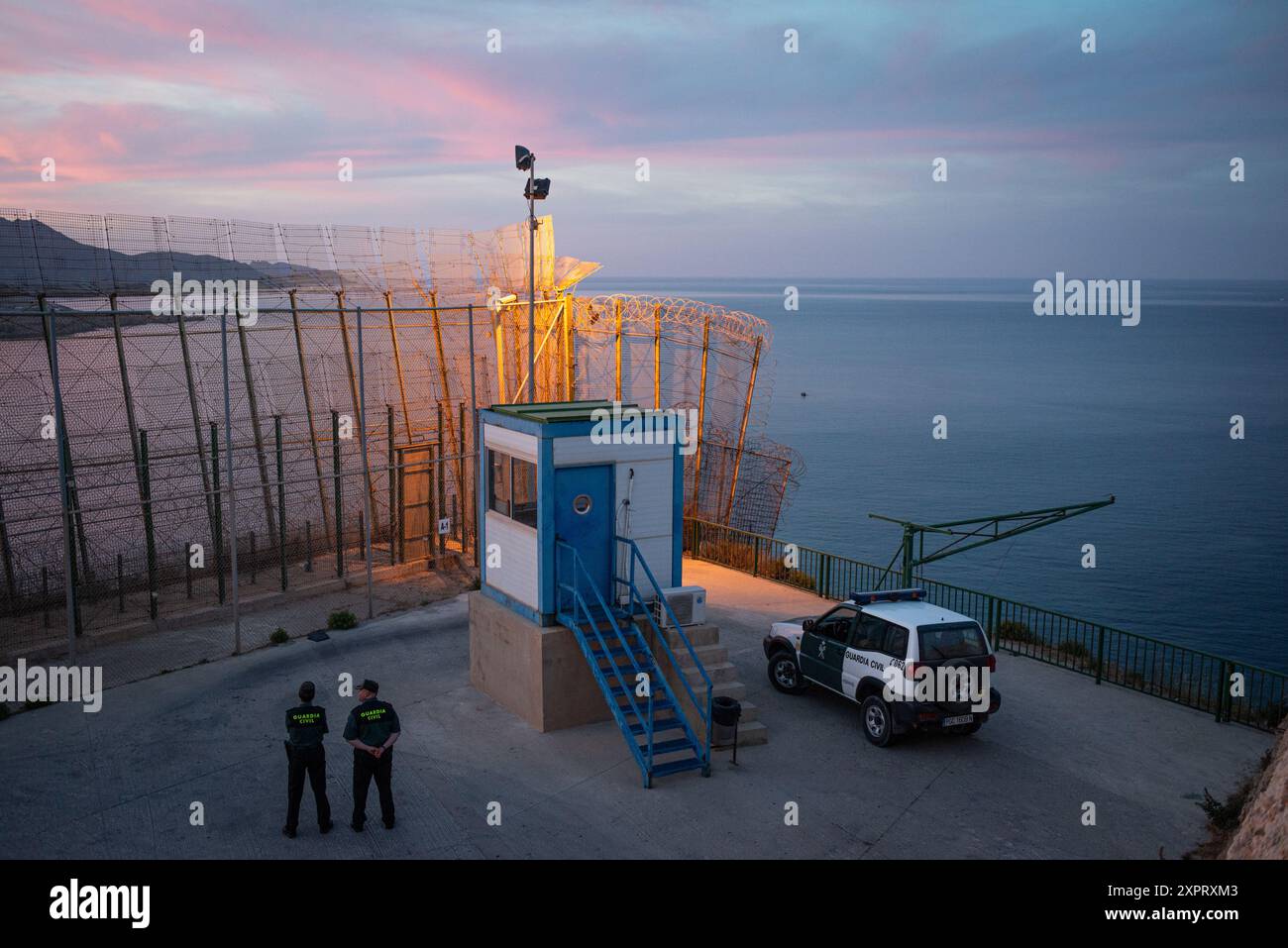 Les officiers civils de la Guardia se tiennent près d'un poste de surveillance frontalier à la frontière extérieure de l'Union européenne avec l'Afrique, dans l'enclave espagnole de Melilla, lors d'un coucher de soleil serein en juin 2012. Banque D'Images