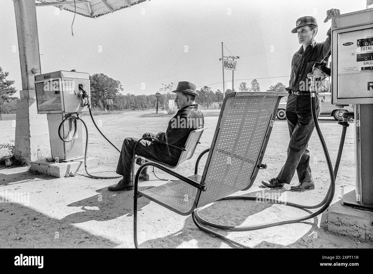 Macédoine, Arkansas, États-Unis – 23 juin 2024 : tir horizontal de deux hommes attendant le prochain client qui a besoin d'essence en 1975. L'un est assis th Banque D'Images