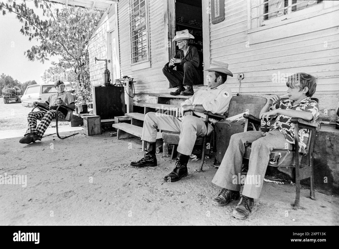 Macédoine, Arkansas, États-Unis – 23 juin 2024 : photo horizontale d'amis assis et parlant devant un vieux magasin des années 1970. Banque D'Images