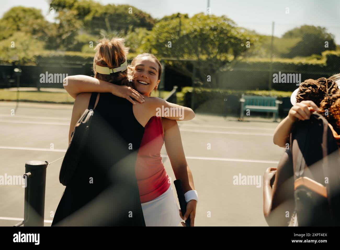 Groupe de joueuses de tennis féminines embrassant et célébrant sur le court de tennis, exprimant amitié et joie après un match Banque D'Images