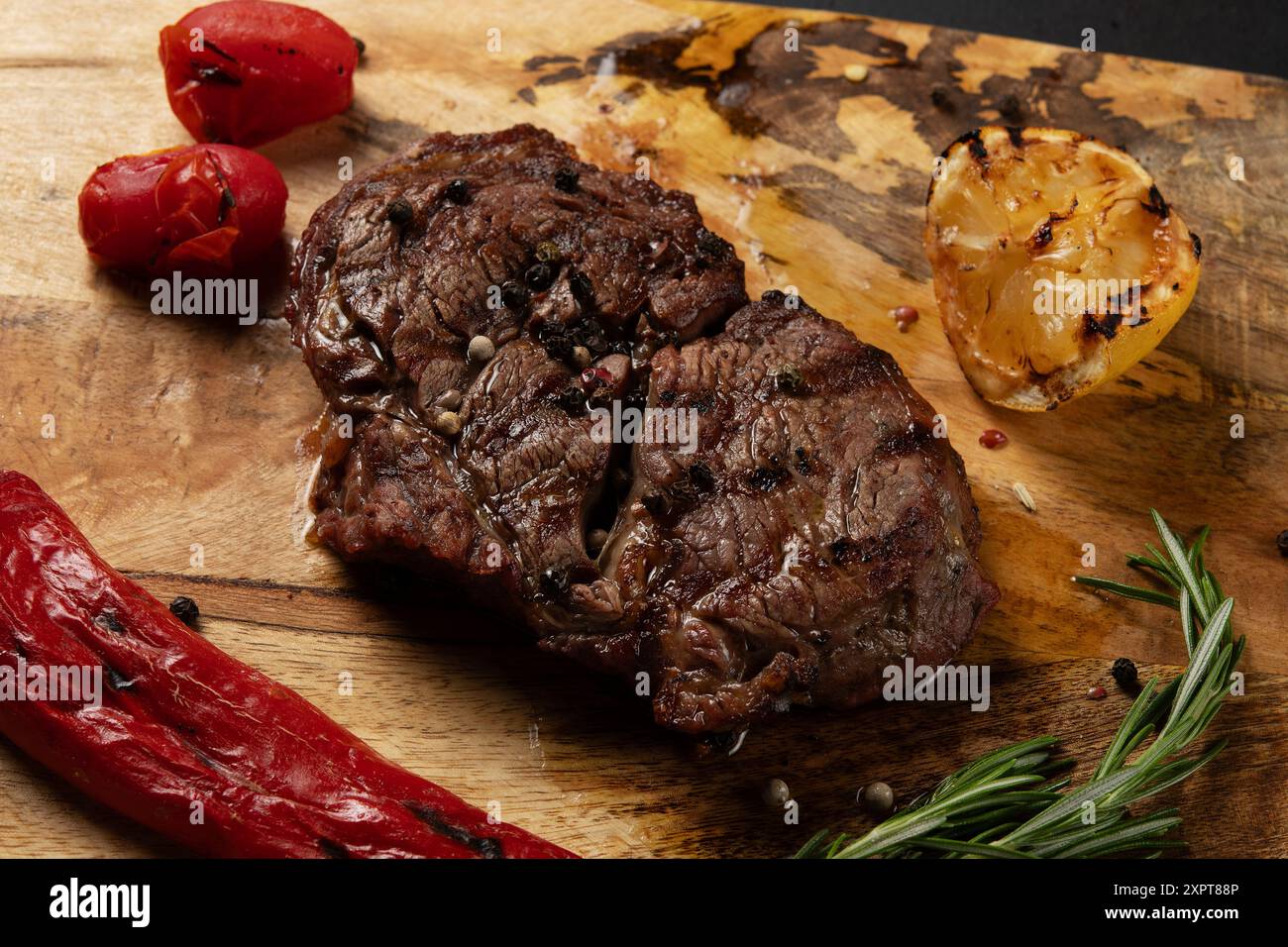 Gros plan grillé Rib Eye Black Angus servi avec du poivre et des herbes sur fond de bois. Banque D'Images