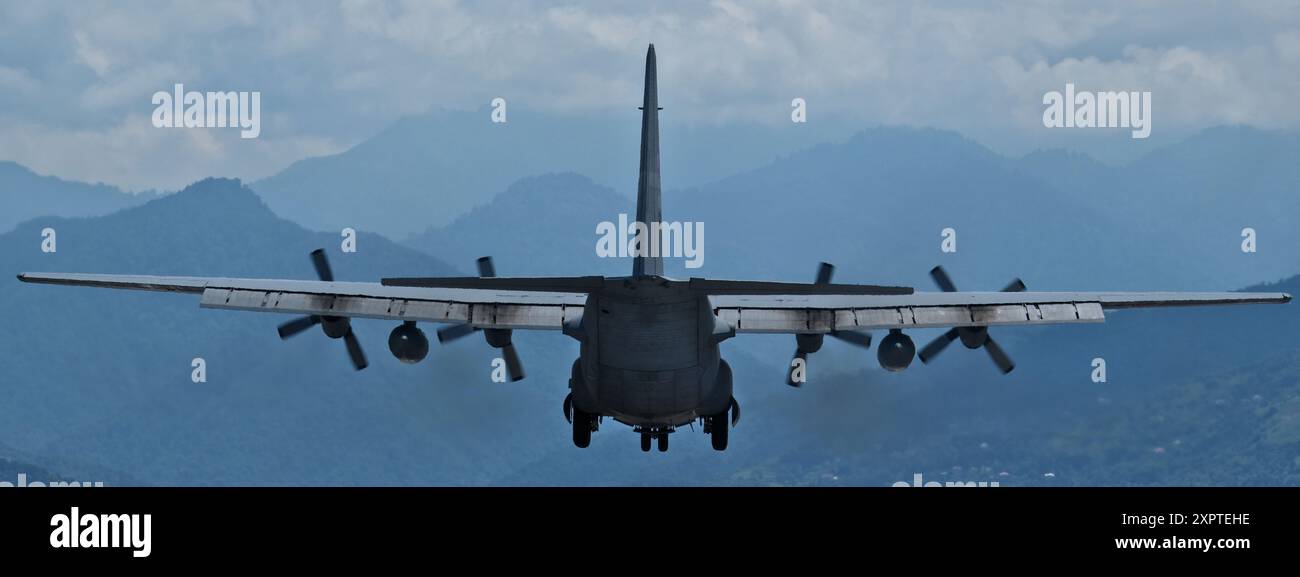 Un avion de transport militaire approche pour atterrir sur fond de montagnes. Banque D'Images
