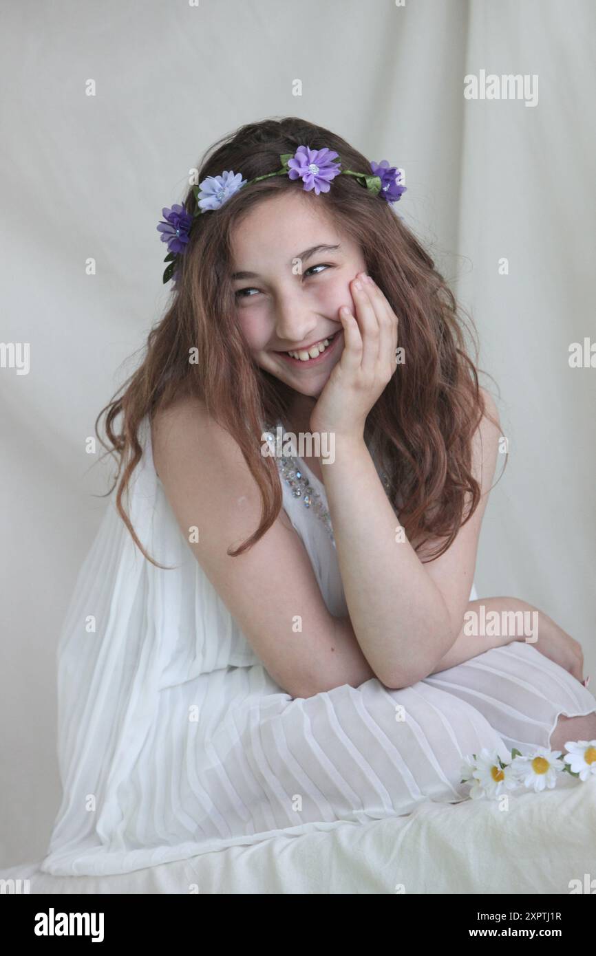 jeune fille preteen joyeuse portant une robe blanche et une bande de tête de fleur Banque D'Images