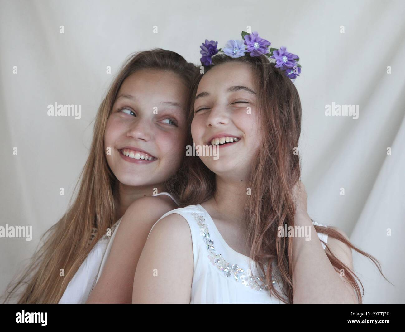 deux filles preteen joyeuses portant des robes blanches sur fond clair Banque D'Images