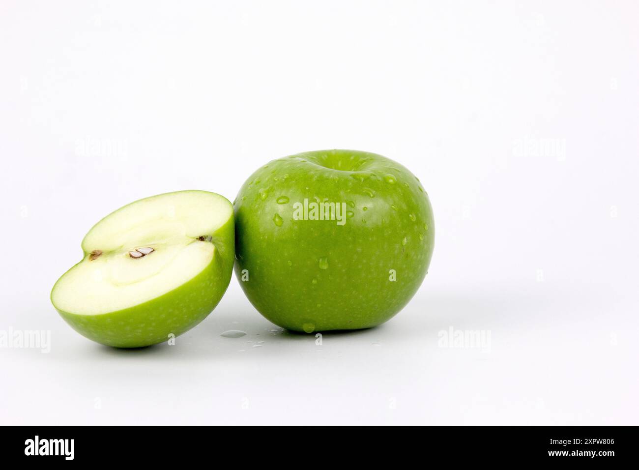 Une pomme fraîche verte et à moitié inclinée isolée sur fond blanc, pleine profondeur de champ, et conception de chemin de détourage Banque D'Images