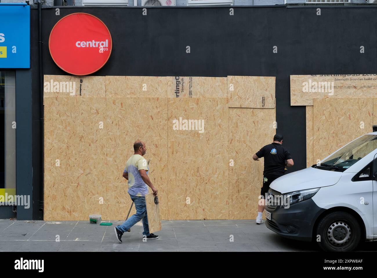 Londres, Royaume-Uni, 7 août 2024. Un travailleur monte à bord d'un magasin alors que les commerces ferment tôt avant une éventuelle manifestation d'extrême droite contre l'immigration et une contre-manifestation antiraciste prévue à Walthamstow. Une liste de 39 bureaux de soutien à l'immigration et d'avocats a été diffusée sur les médias sociaux pour encourager les manifestations aux adresses fournies. Crédit : onzième heure photographie/Alamy Live News Banque D'Images