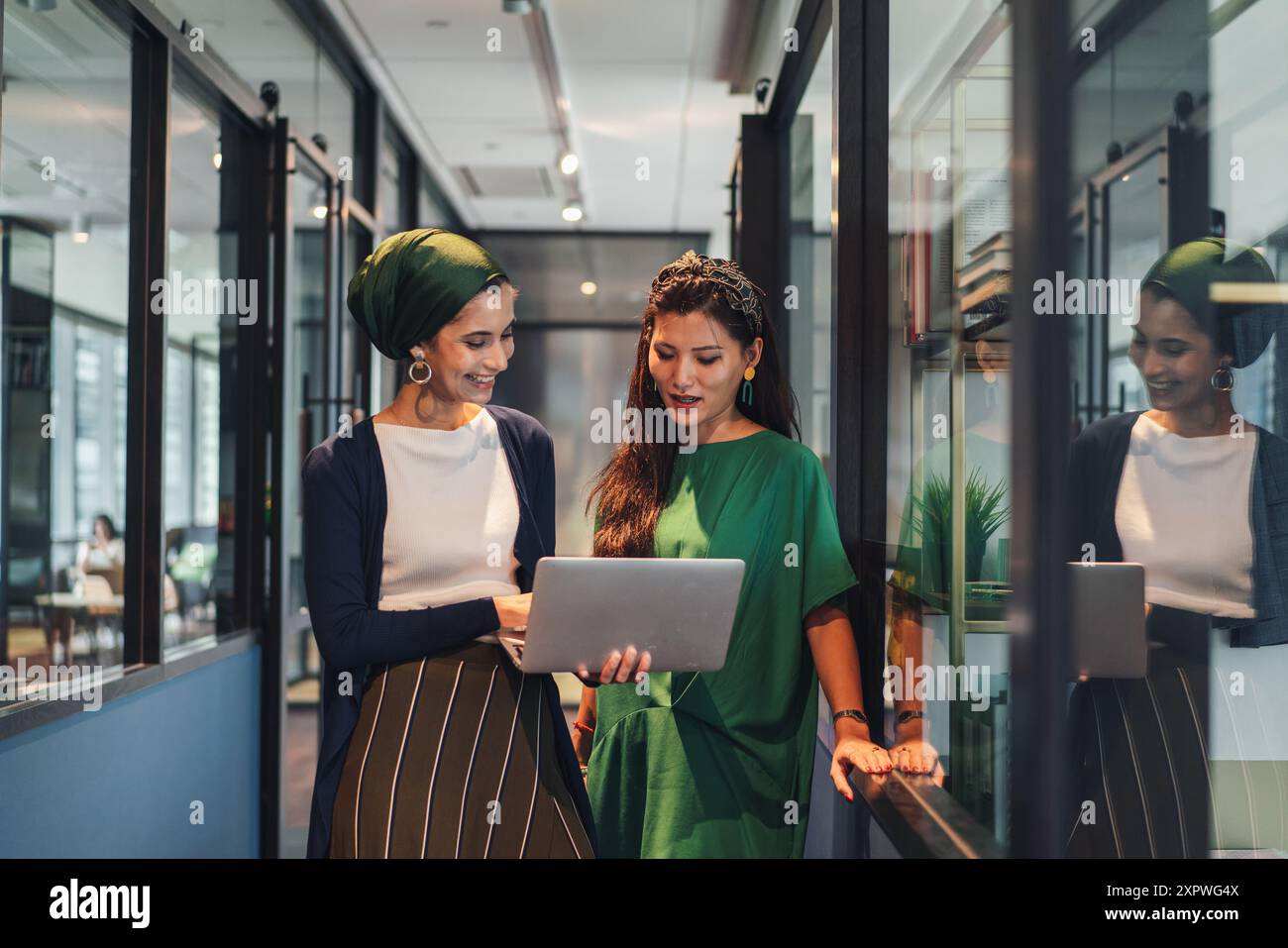 Deux femmes d'affaires asiatiques en tenue décontractée discutant du travail dans le couloir du bureau Banque D'Images