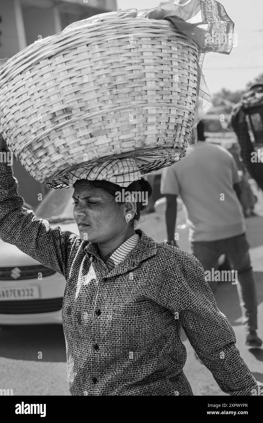 Femme portant un panier sur sa tête Goa India. Femme indienne avec un grand panier sur la tête. En Inde, c'est une façon populaire d'apporter des choses lourdes. Baguette dure Banque D'Images