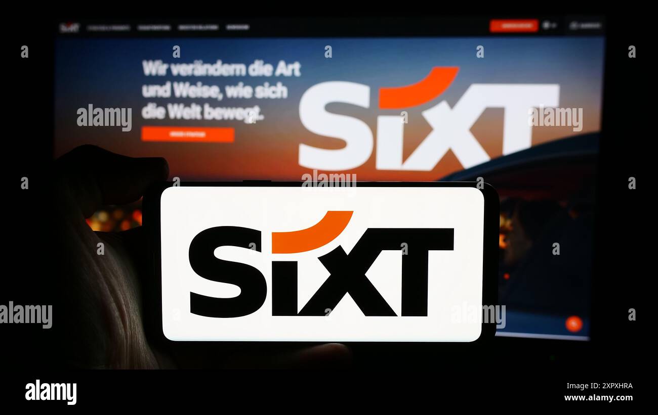 Personne tenant le téléphone portable avec le logo de la société de location de voitures allemande Sixt se en face de la page Web de l'entreprise. Concentrez-vous sur l'affichage du téléphone. Banque D'Images