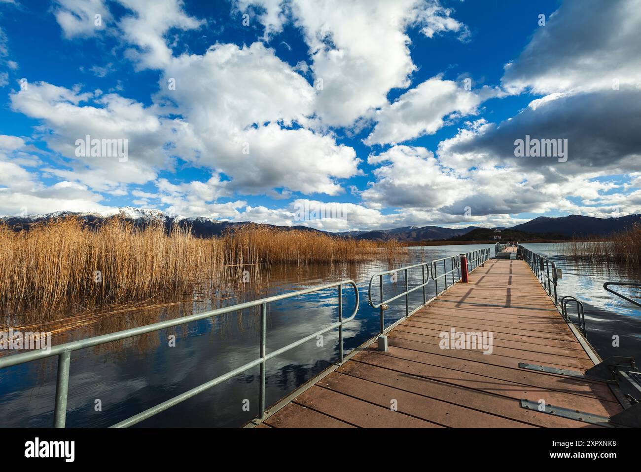 Le pont flottant en bois vers l'îlot d'Agios Achillios, dans le petit lac de Prespa, en Grèce, pendant une journée fraîche d'hiver avec un ciel de nuages blancs étonnants Banque D'Images